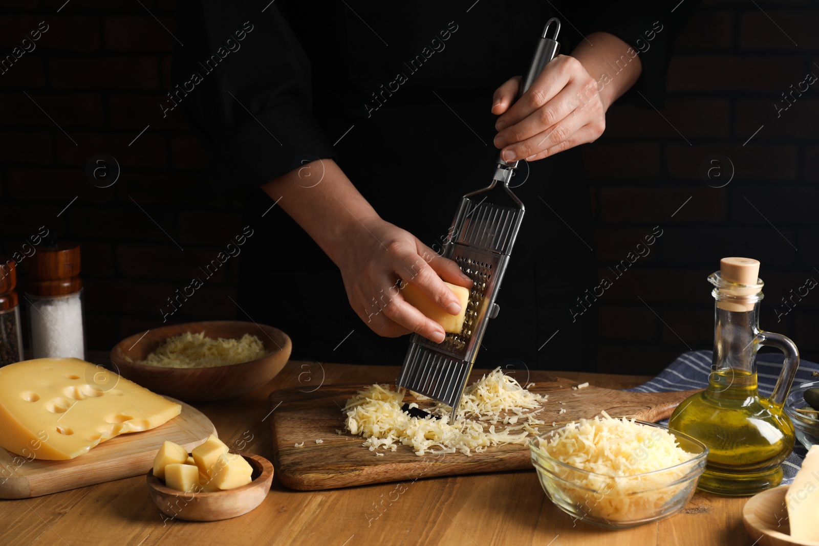 Photo of Woman grating cheese at wooden table, closeup