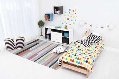 Modern child room interior with comfortable bed and striped carpet