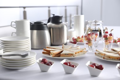 Table with different delicious snacks and dishware indoors. Coffee break