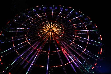Beautiful glowing Ferris wheel against dark sky, low angle view