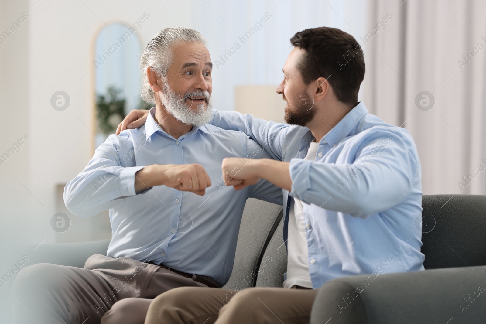Photo of Happy son and his dad making fist bump at home