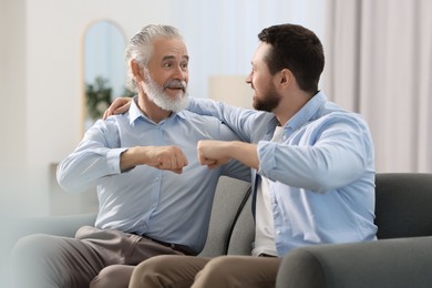 Happy son and his dad making fist bump at home