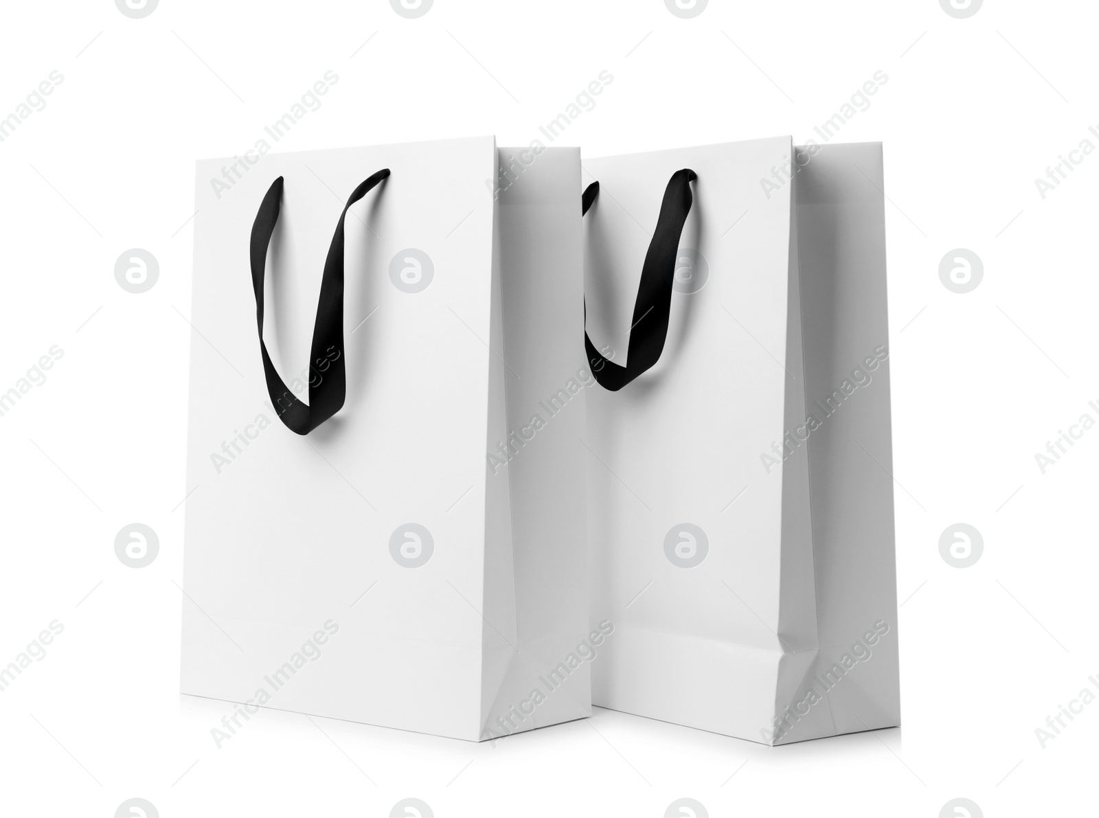 Photo of Paper shopping bags with ribbon handles on white background. Mockup for design