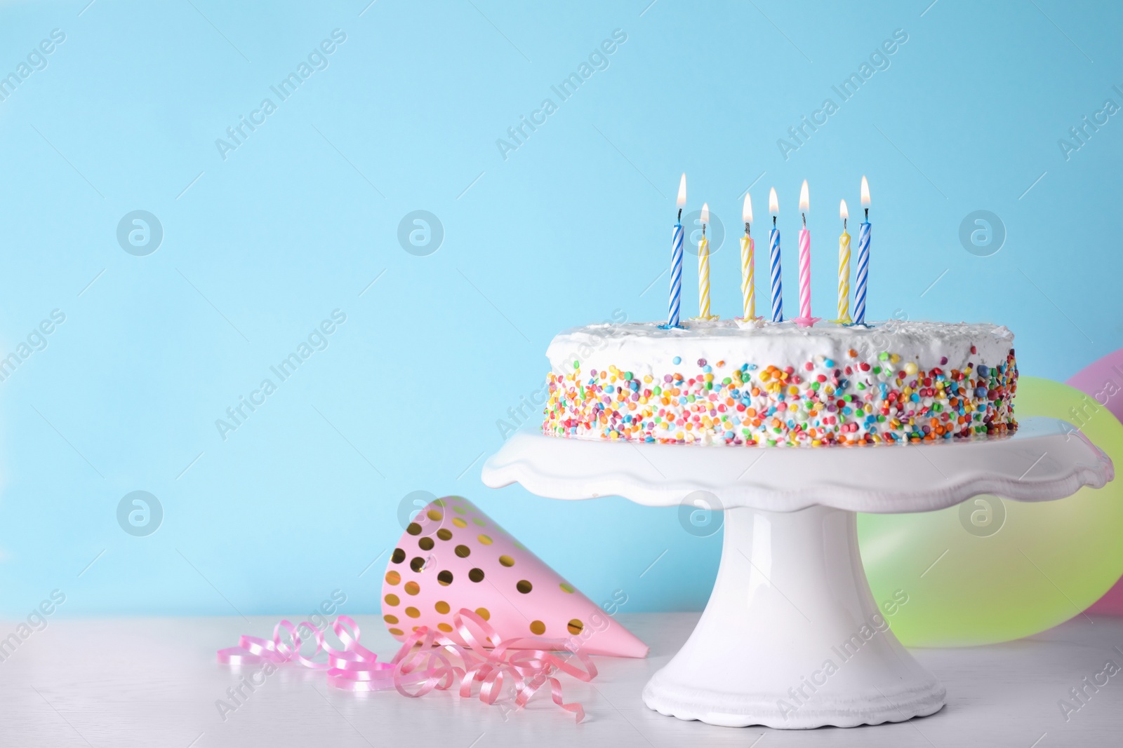 Photo of Birthday cake with burning candles on table against color background. Space for text