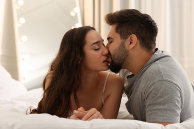 Photo of Passionate young couple kissing on bed indoors