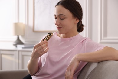 Woman eating tasty granola bar at home