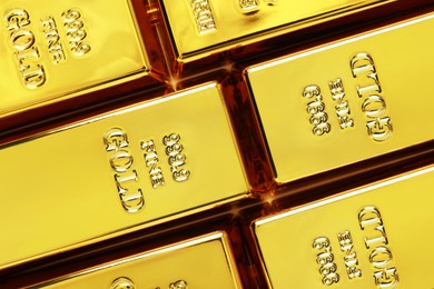 Photo of Many shiny gold bars as background, top view