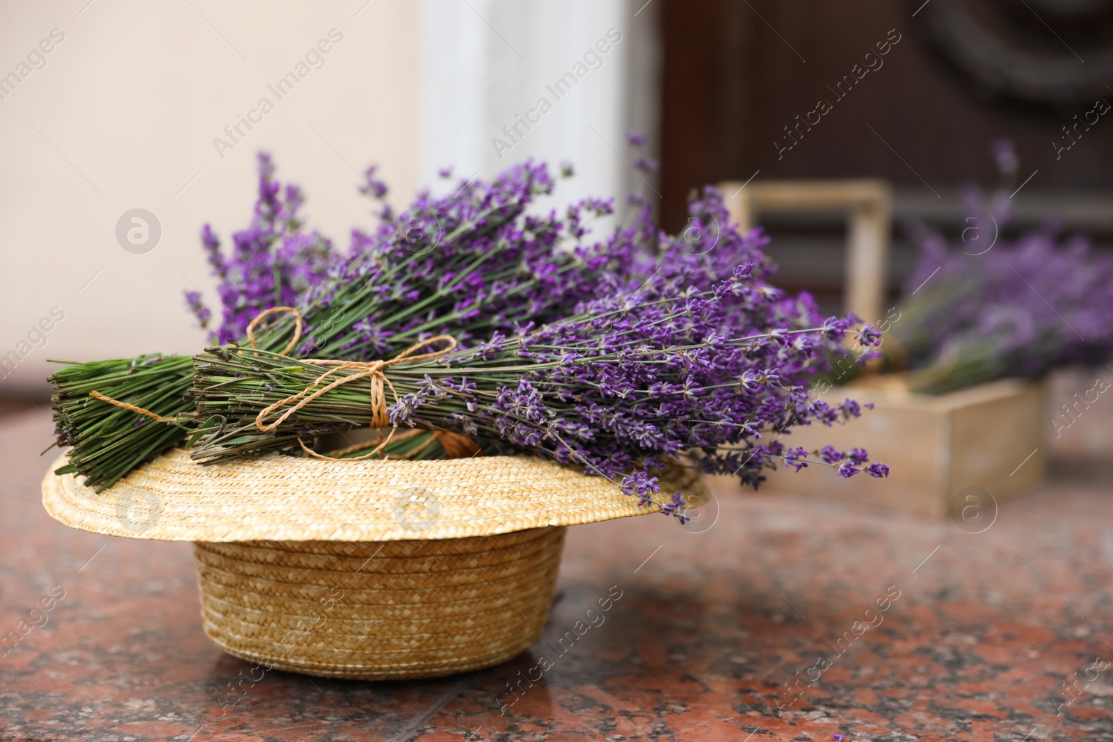 Photo of Beautiful lavender flowers and straw hat on marble tiles outdoors