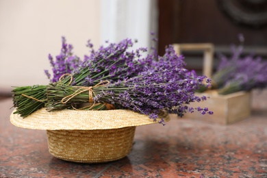 Beautiful lavender flowers and straw hat on marble tiles outdoors