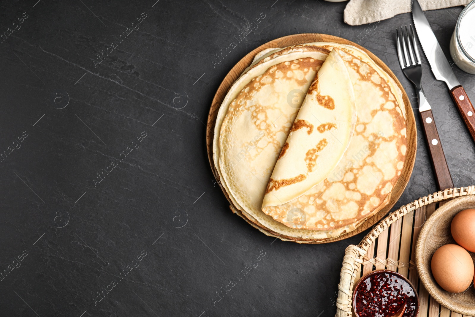 Photo of Flat lay composition with fresh thin pancakes on black table. Space for text