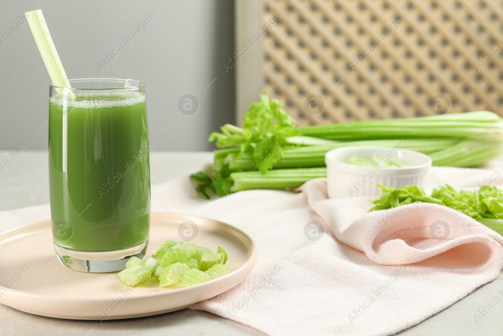 Photo of Glass of delicious celery juice and vegetables on grey table, closeup. Space for text