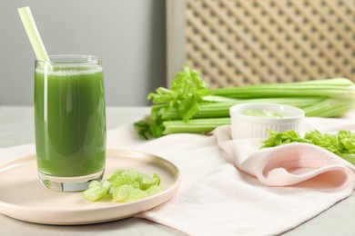 Photo of Glass of delicious celery juice and vegetables on grey table, closeup. Space for text