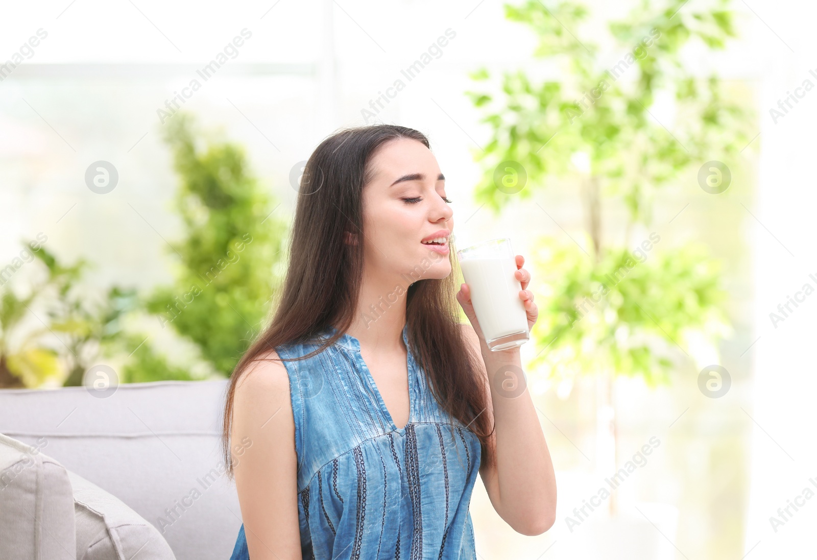 Photo of Beautiful young woman drinking milk at home