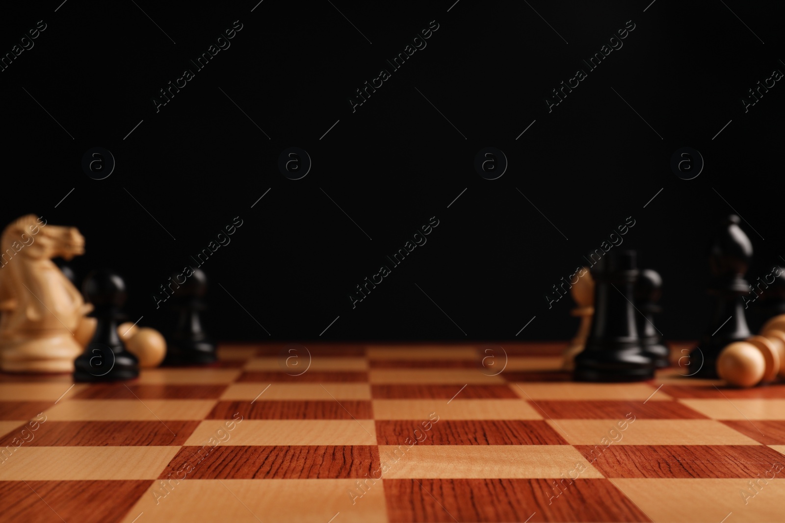 Photo of Many chess pieces on wooden checkerboard against black background, selective focus. Space for text