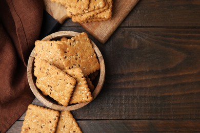 Photo of Cereal crackers with flax and sesame seeds on wooden table, flat lay. Space for text