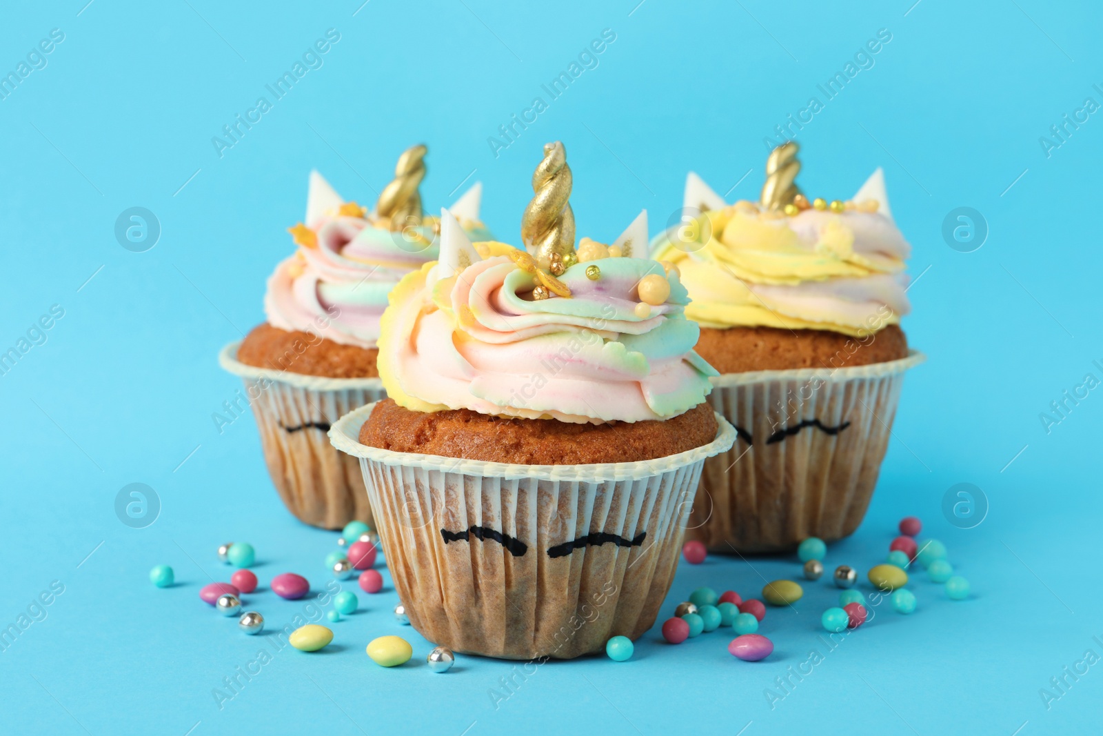 Photo of Cute sweet unicorn cupcakes on light blue background