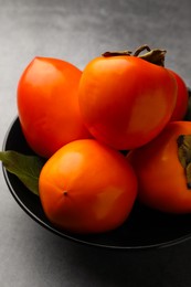 Photo of Delicious ripe persimmons in bowl on light gray table