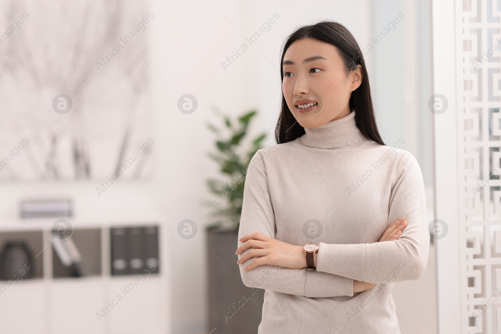 Photo of Portrait of smiling businesswoman with crossed arms in office. Space for text