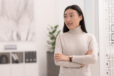 Portrait of smiling businesswoman with crossed arms in office. Space for text