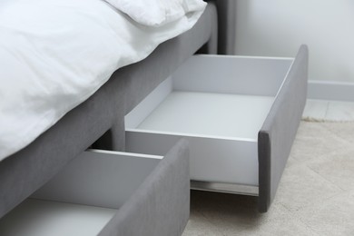 Photo of Storage drawers for bedding under modern bed in room, closeup