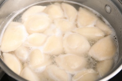 Photo of Cooking dumplings (varenyky) with cottage cheese in pot, closeup