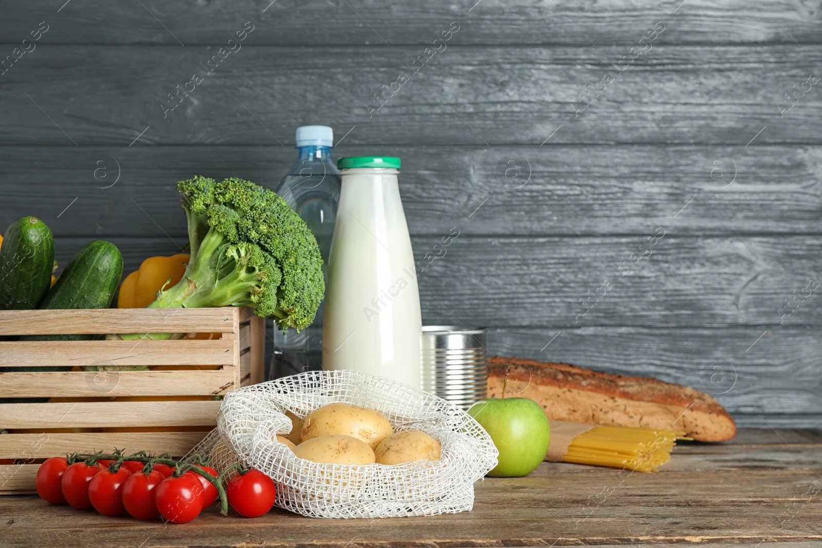 Photo of Different fresh vegetables and fruits on wooden table against dark background