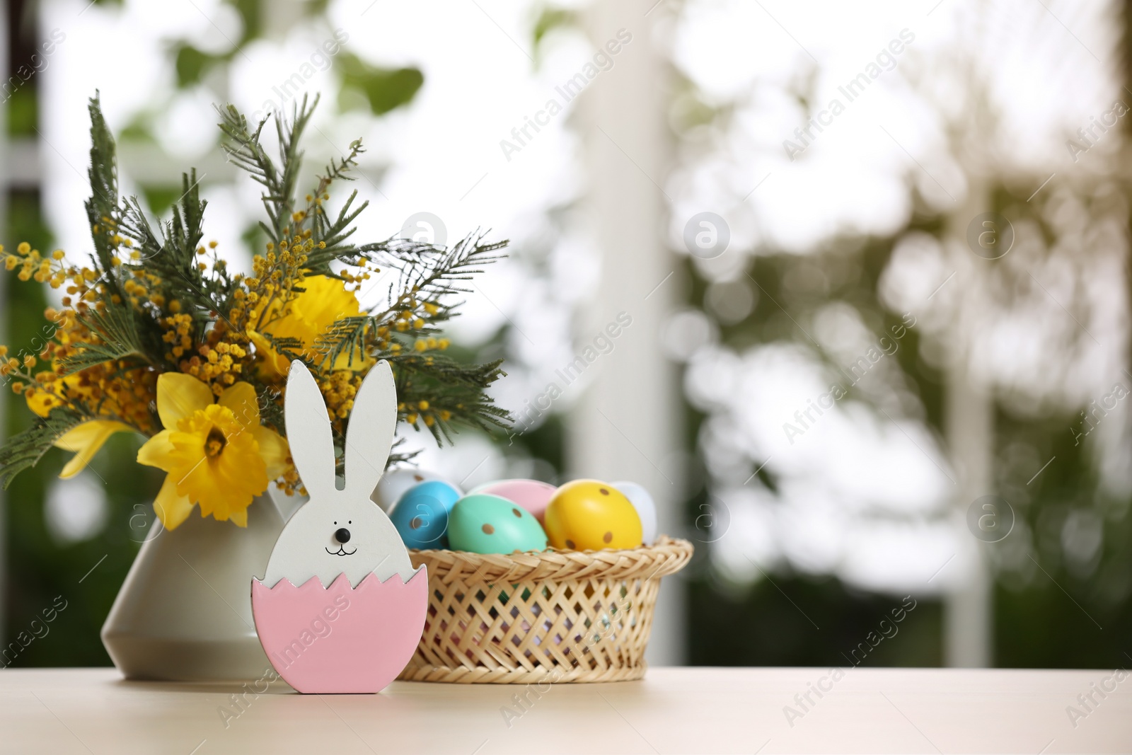 Photo of Festive composition with Easter eggs on table against blurred window, space for text