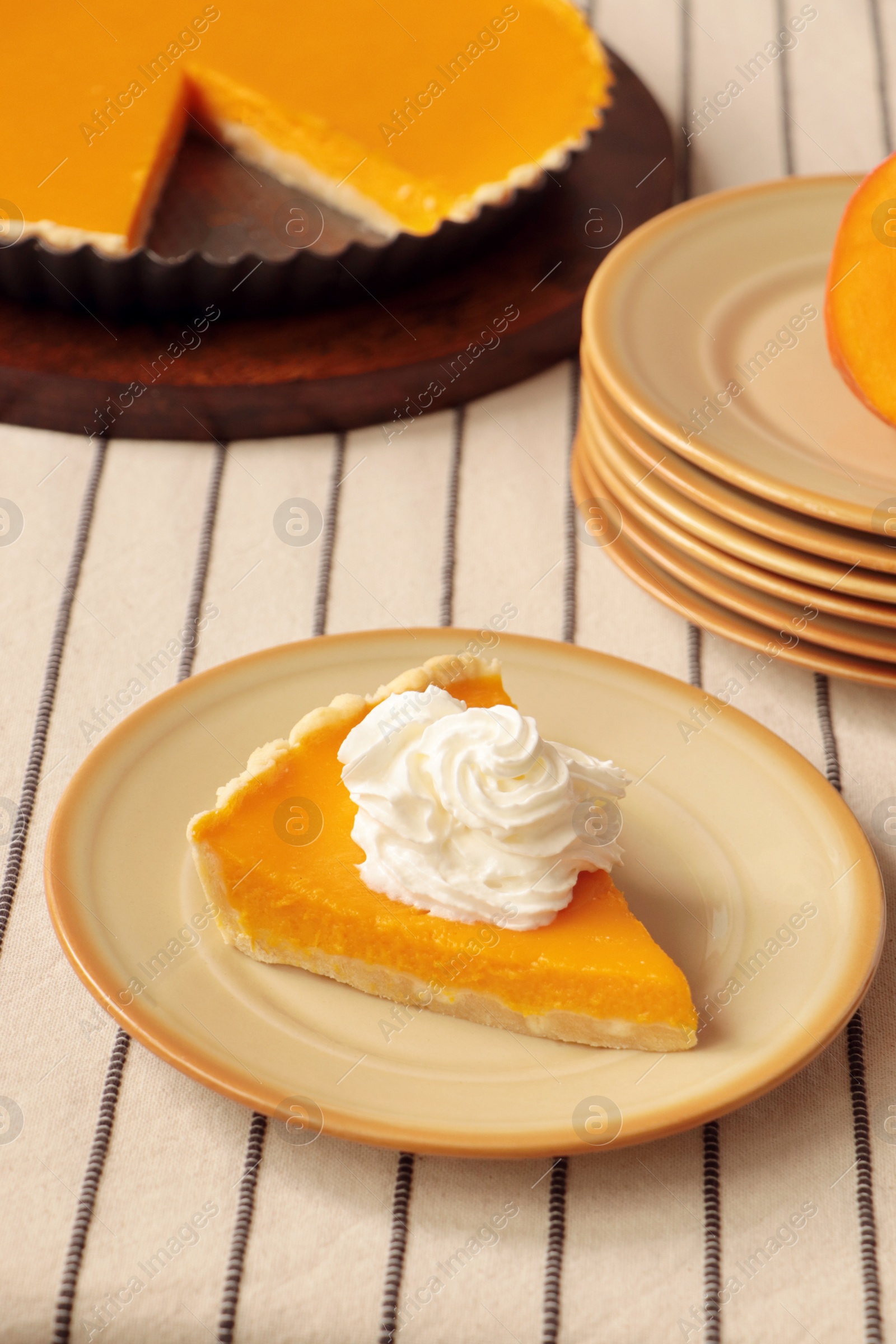 Photo of Piece of fresh homemade pumpkin pie with whipped cream on table