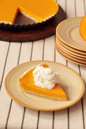 Piece of fresh homemade pumpkin pie with whipped cream on table