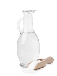 Photo of Vinegar in glass jug, baking soda and wooden scoop isolated on white