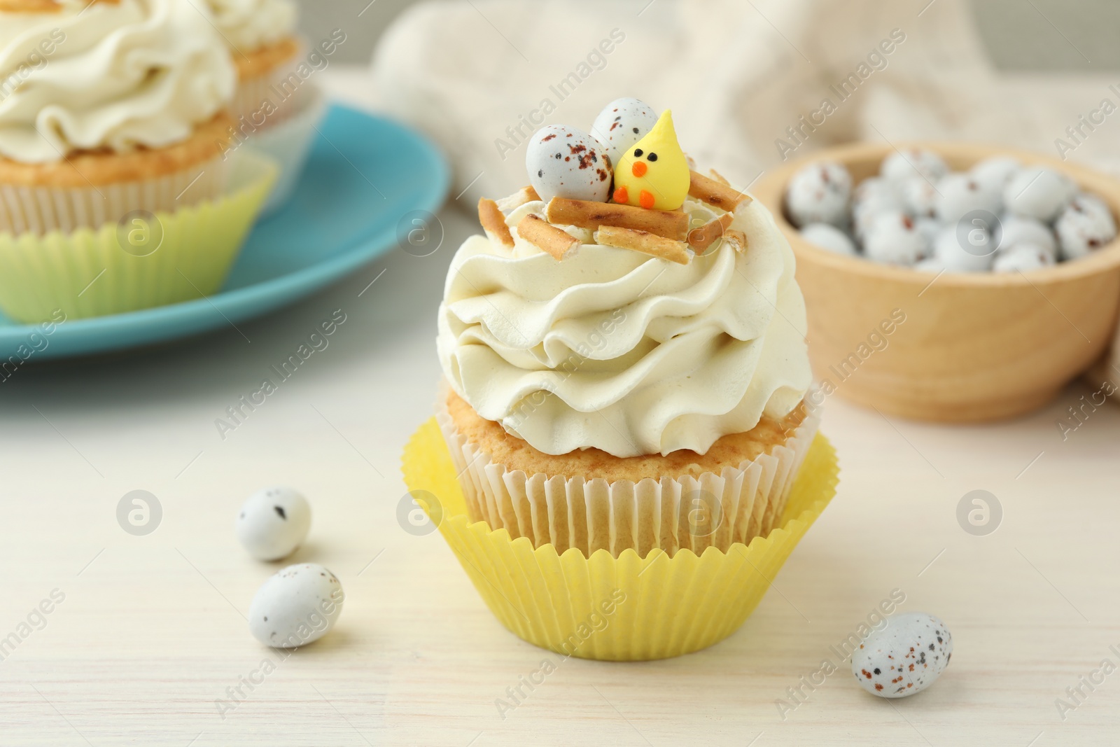 Photo of Tasty Easter cupcakes with vanilla cream on light wooden table