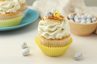 Photo of Tasty Easter cupcakes with vanilla cream on light wooden table