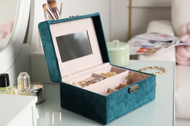 Elegant jewelry box with beautiful bijouterie, cosmetics and perfume on dressing table in room