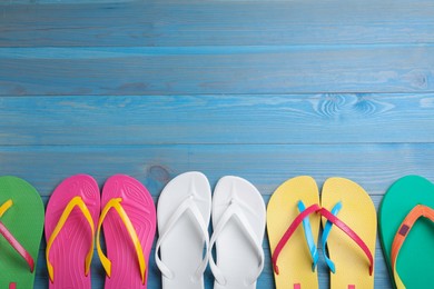 Many different flip flops on light blue wooden background, flat lay. Space for text