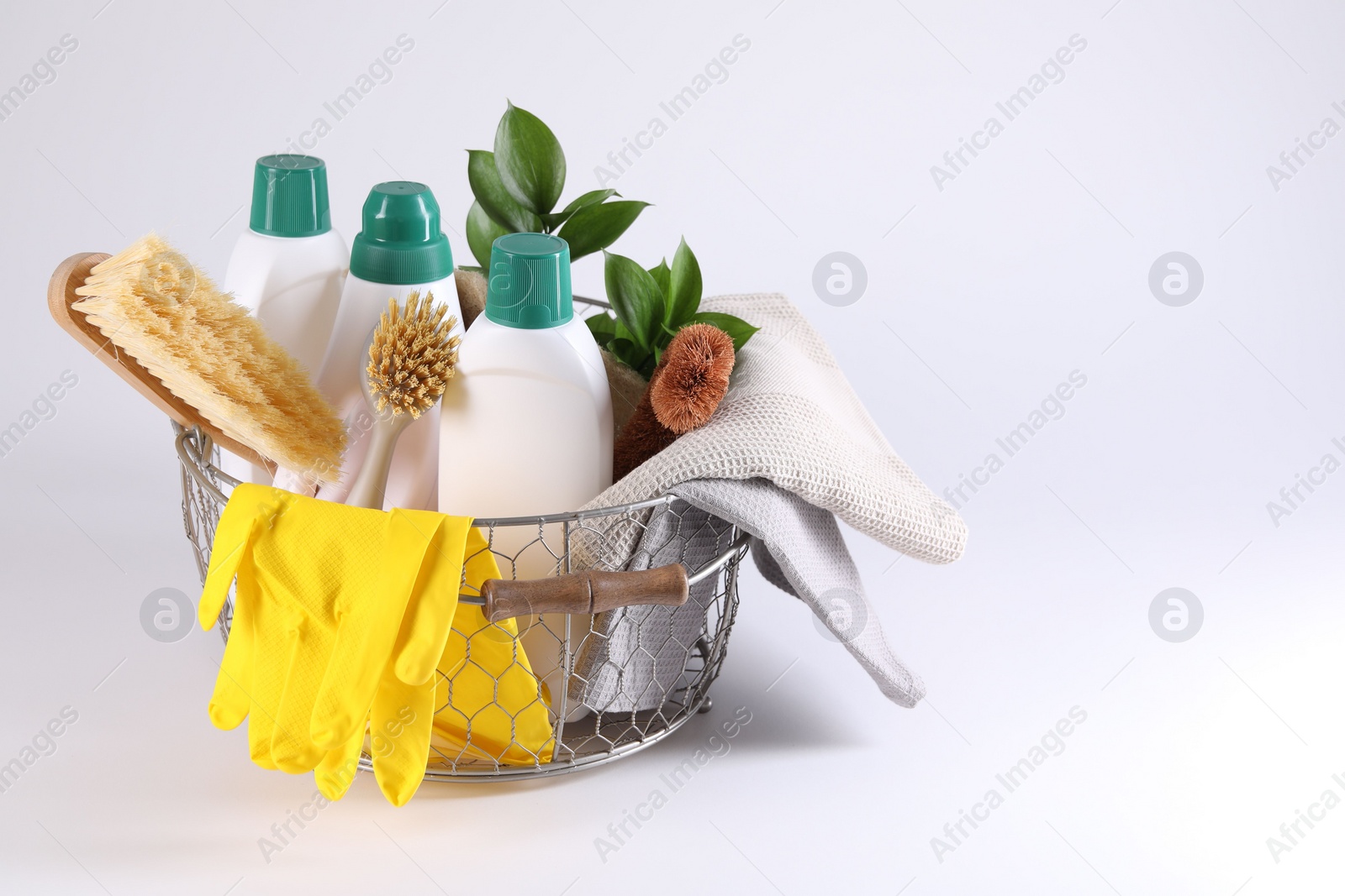 Photo of Set of different cleaning supplies in basket on white background