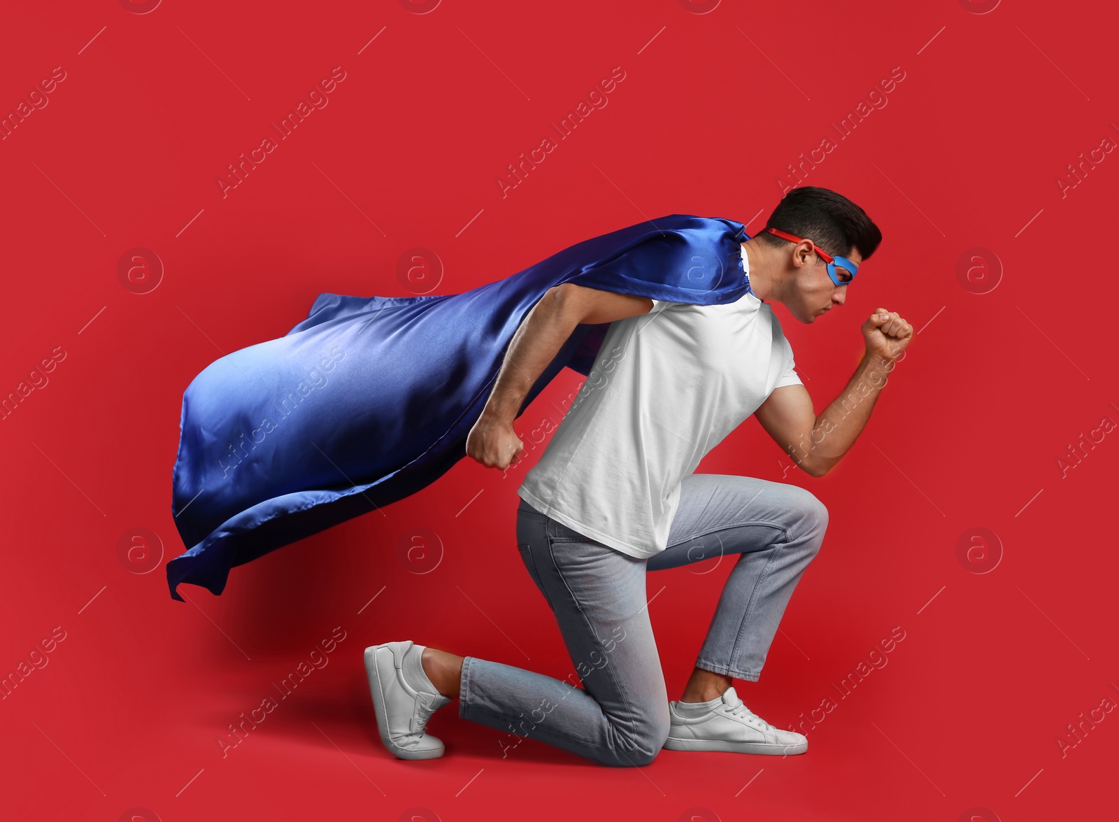 Photo of Man wearing superhero cape and mask on red background