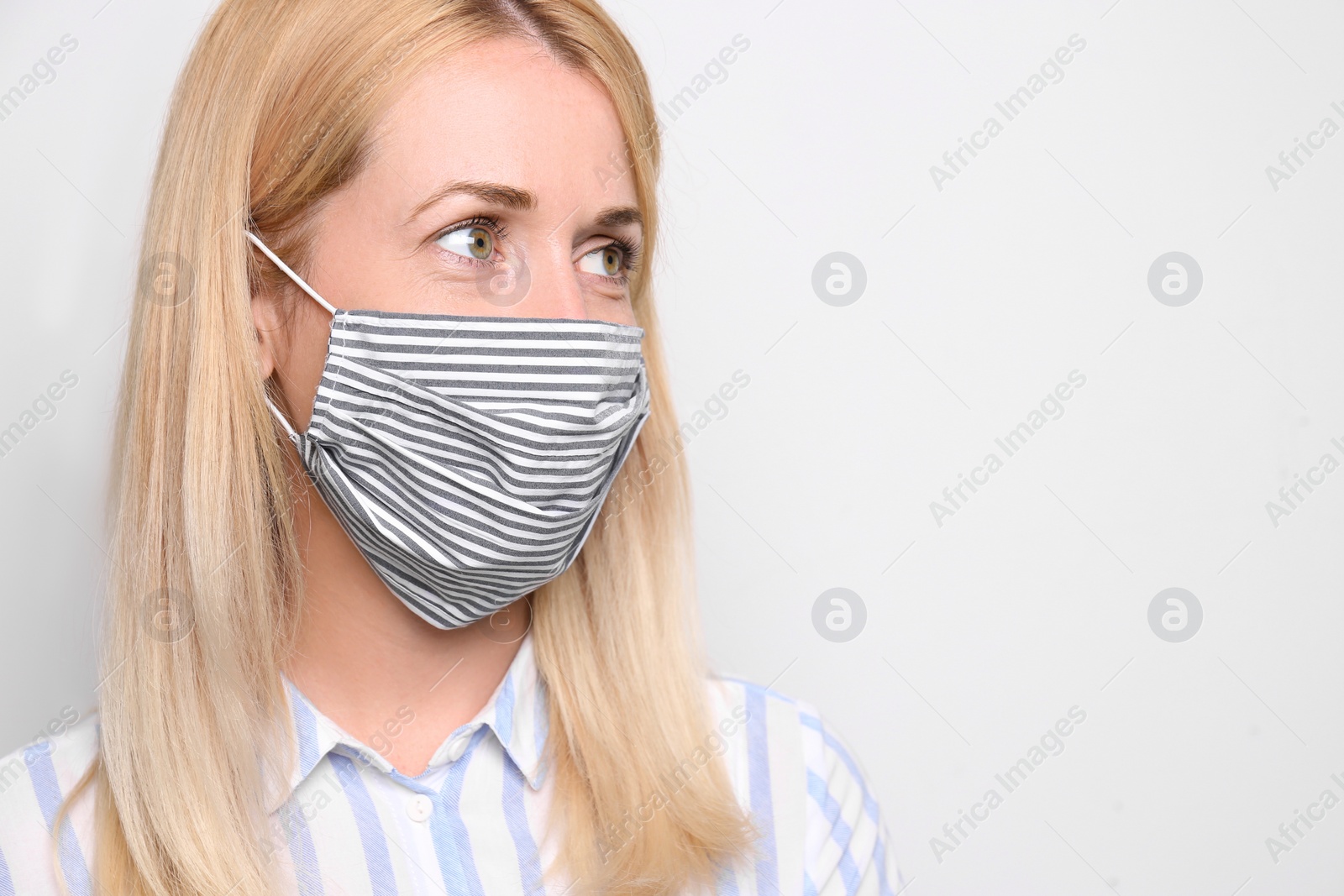 Photo of Woman wearing handmade cloth mask on white background, space for text. Personal protective equipment during COVID-19 pandemic