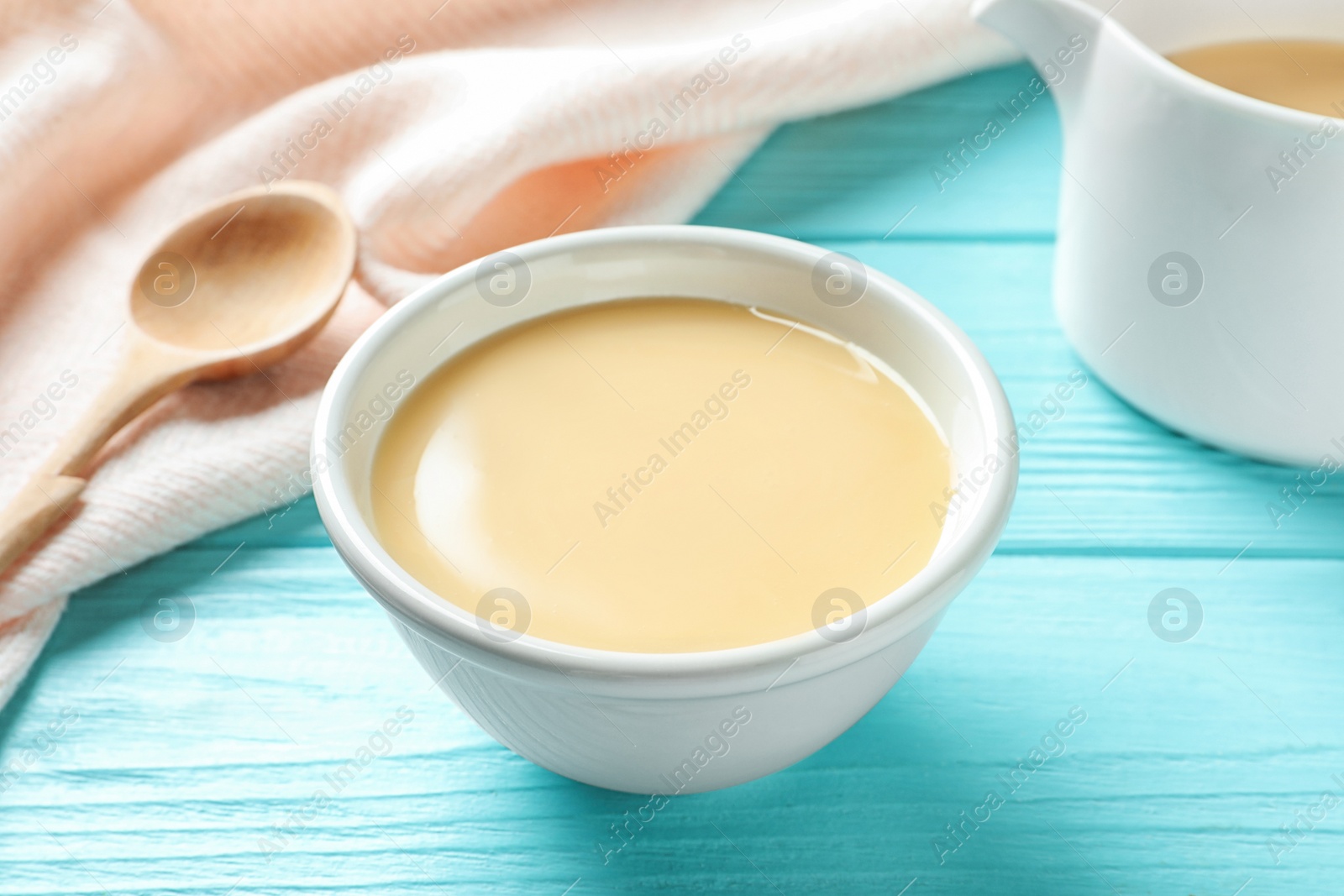 Photo of Bowl with condensed milk on wooden table. Dairy products