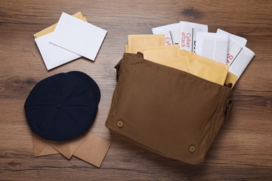 Postman hat, bag, newspapers and mails on wooden table, flat lay