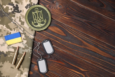 Photo of Flat lay composition with Ukraine military equipment on wooden table, space for text