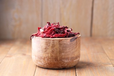 Photo of Dry hibiscus tea in bowl on wooden table