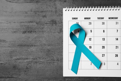 Flat lay composition with teal ribbon and calendar on grey background. Space for text