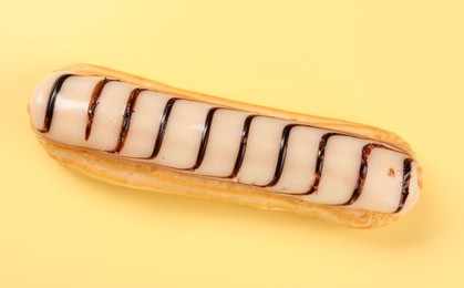 Photo of Delicious eclair covered with glaze on yellow background, top view