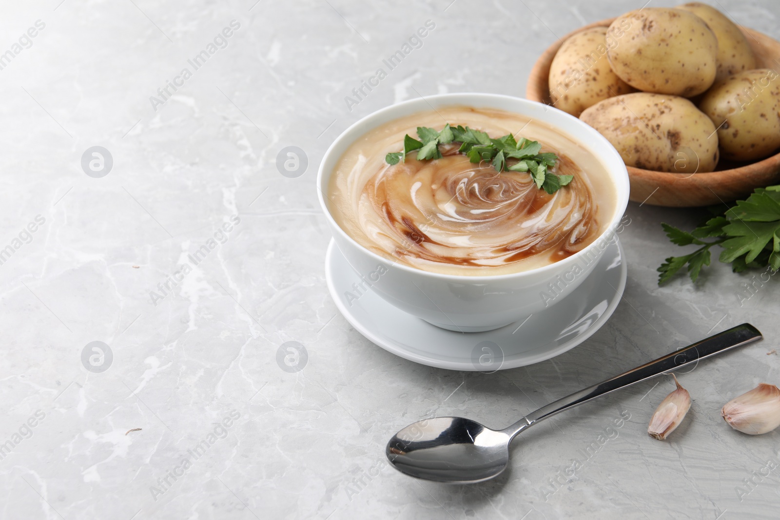 Photo of Delicious cream soup with soy sauce and parsley served on grey marble table. Space for text