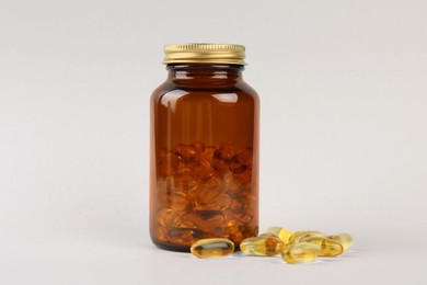 Photo of Jar with vitamin capsules on light grey background