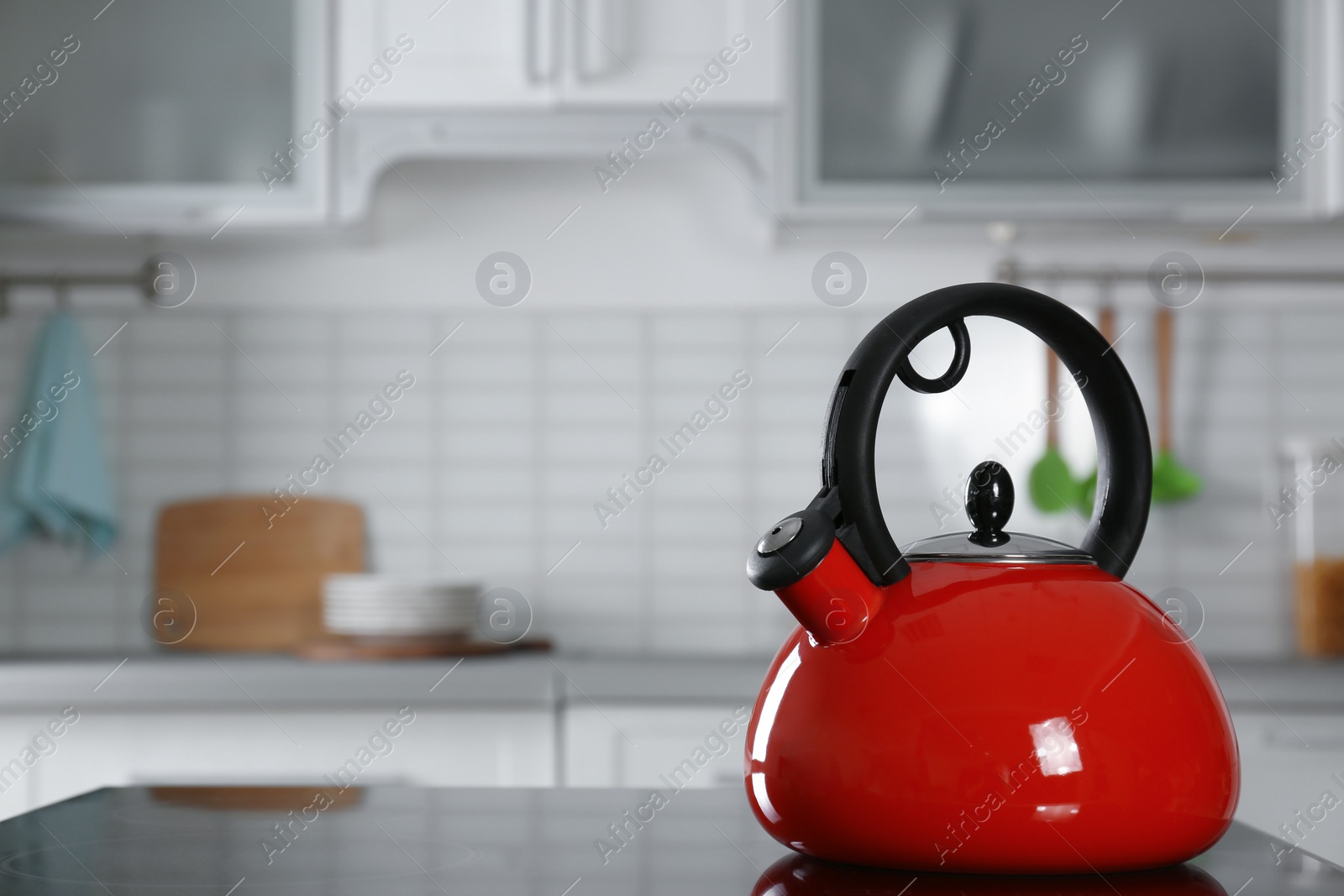 Photo of Modern kettle with whistle on stove in kitchen, space for text