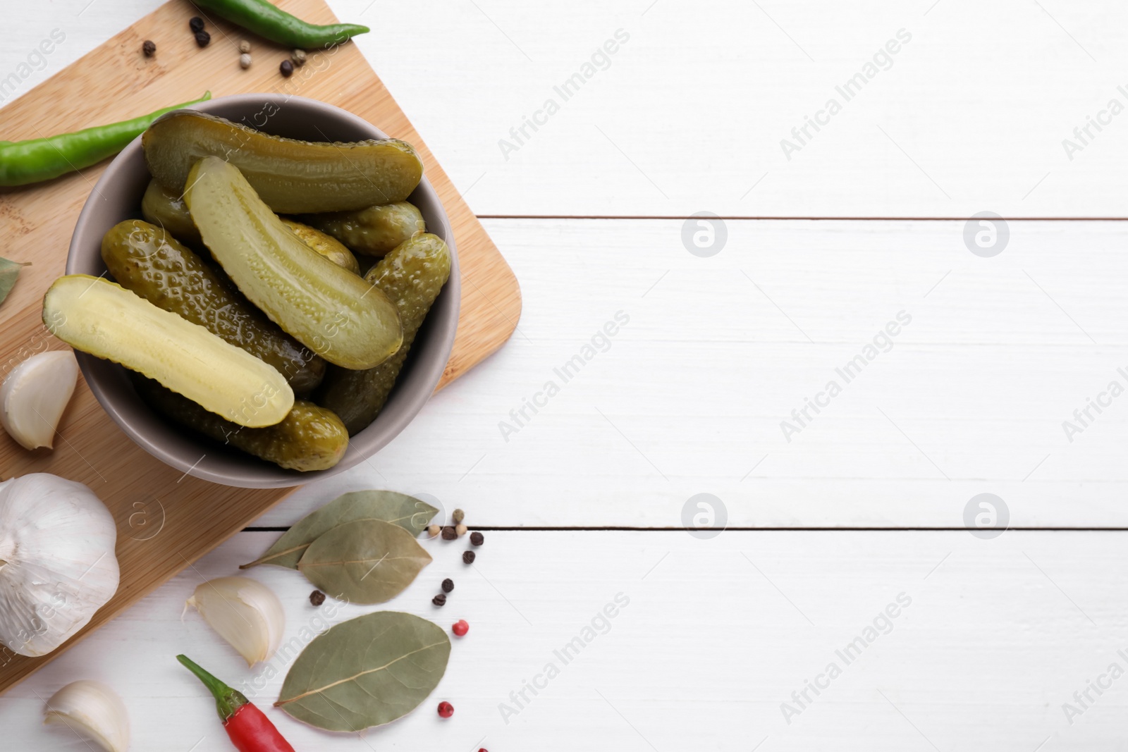 Photo of Tasty pickled cucumbers and ingredients on white wooden table, flat lay. Space for text