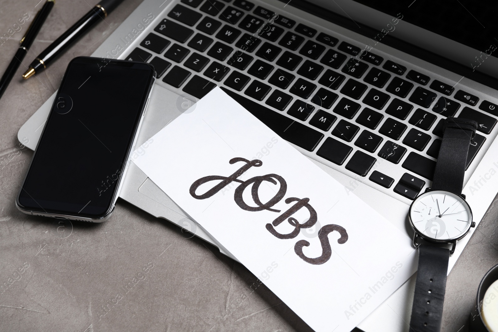 Photo of Composition with word JOBS, laptop and smartphone on grey table. Career concept