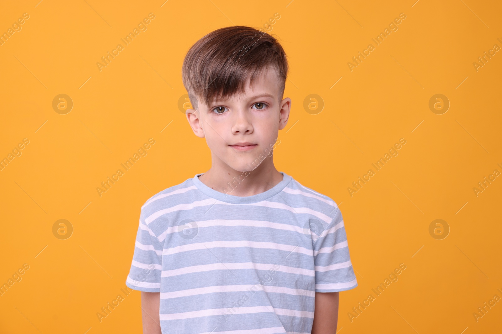 Photo of Portrait of cute boy on orange background