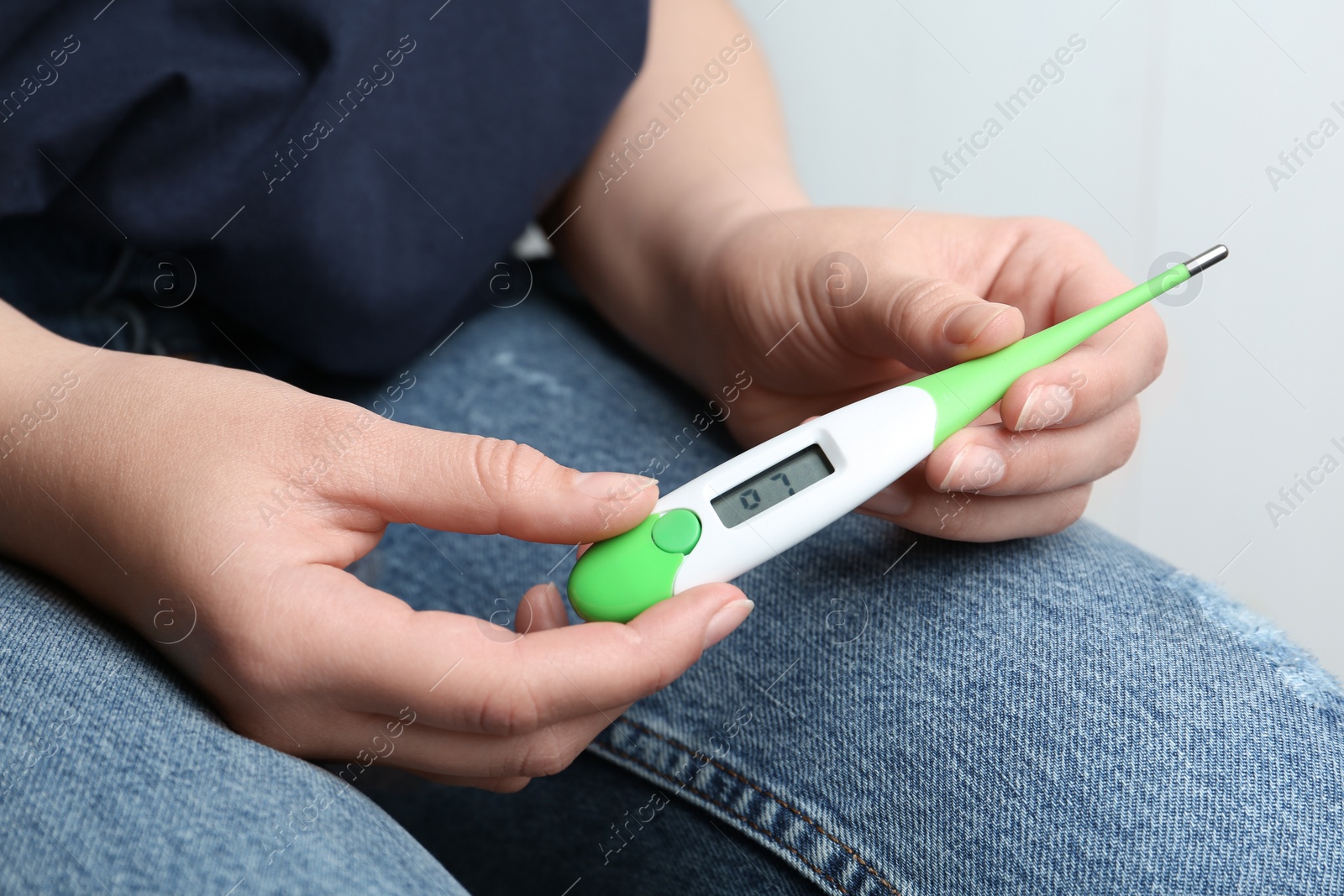 Photo of Woman with digital thermometer on light background, closeup